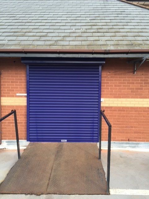 A blue garage door with a ramp leading to it