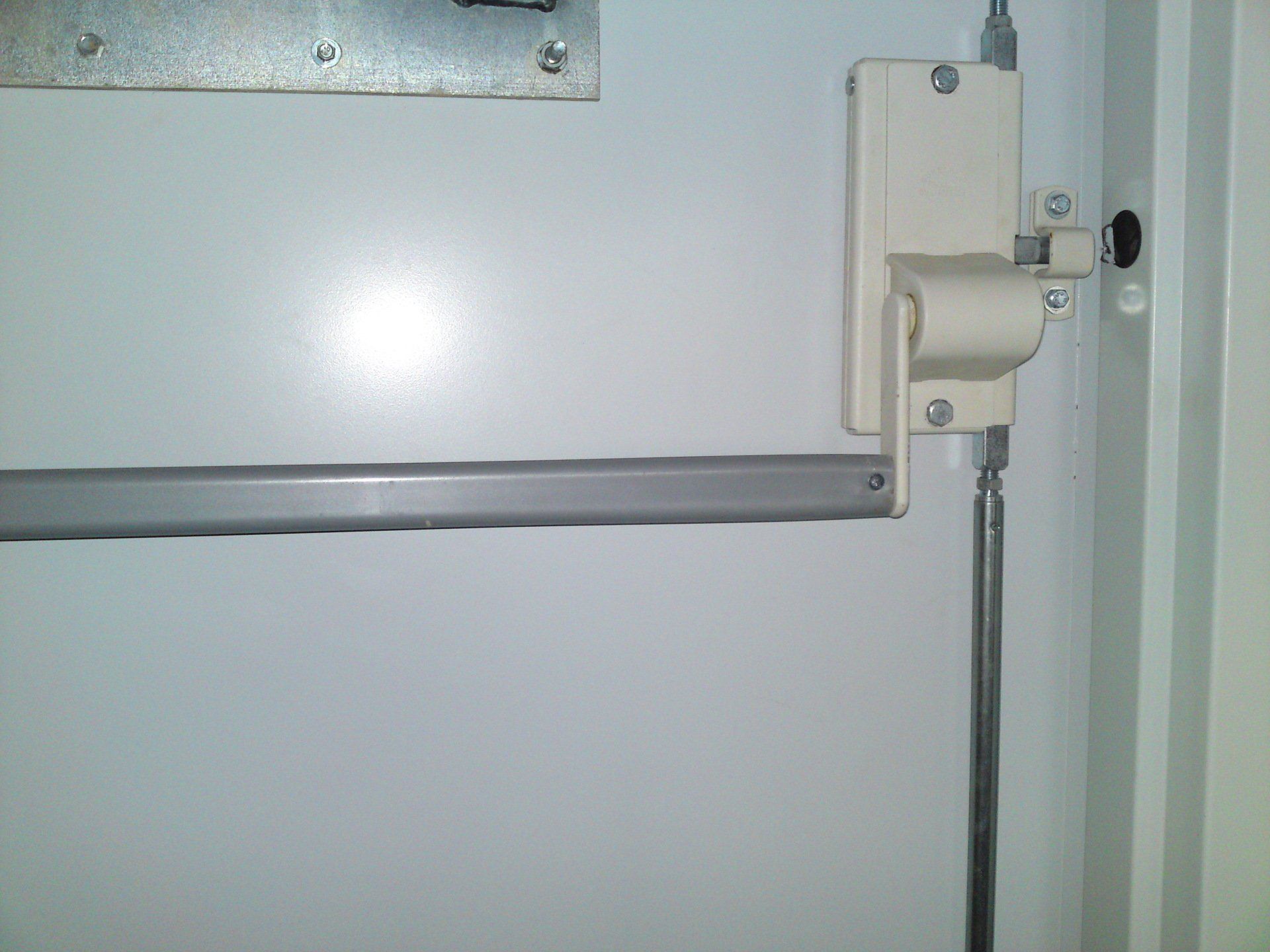 A white door with a metal railing and a metal pipe attached to it.