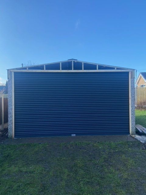 A blue garage door is sitting in the middle of a lush green field.
