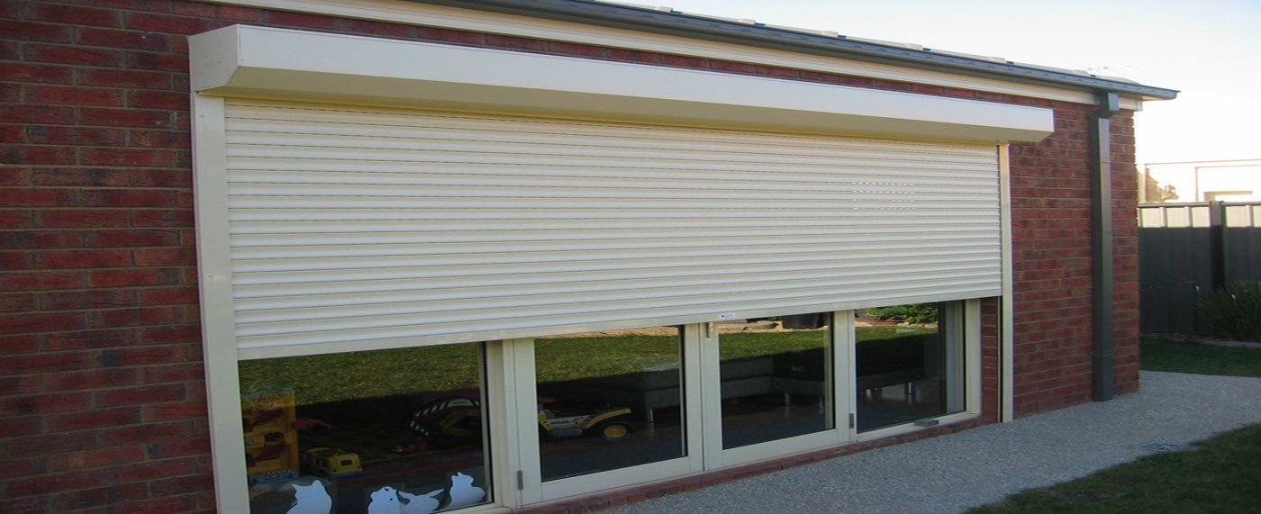A white roller shutter is open on a brick building.