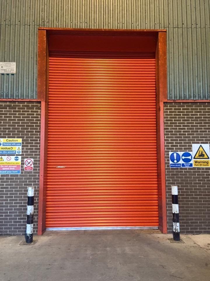 A brick building with an orange door and warning signs
