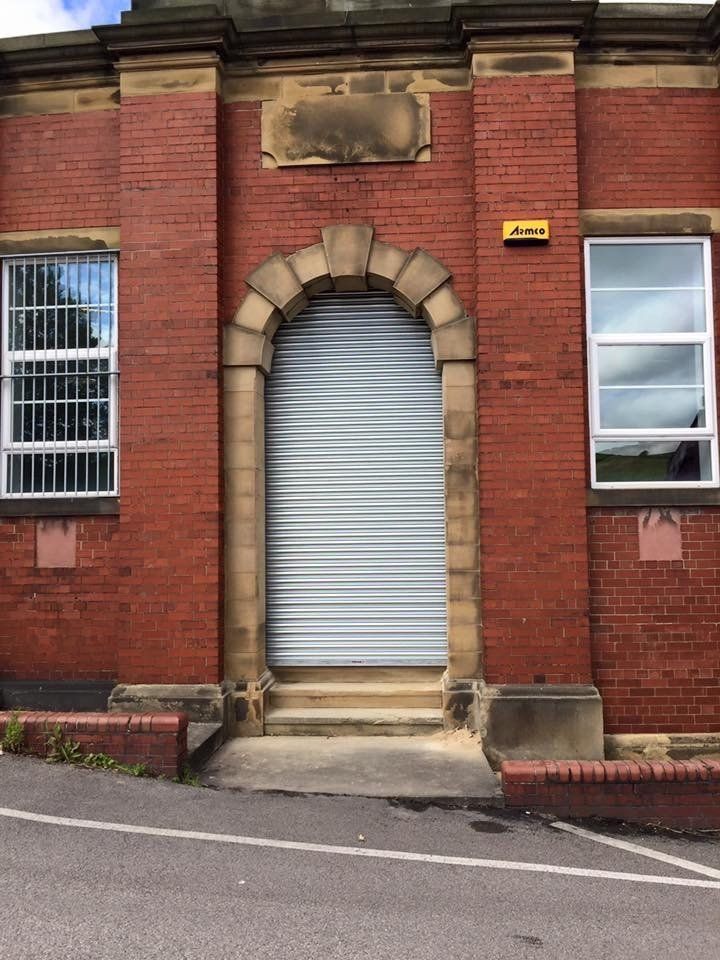 A brick building with a white shutter on the door