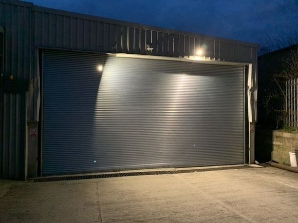 A large garage door is open and lit up at night.