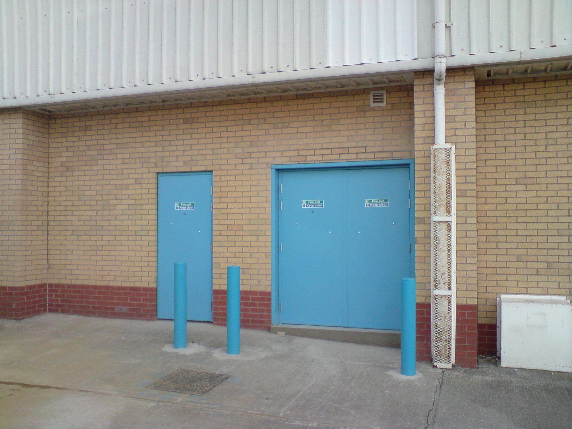 A brick building with blue doors and blue poles
