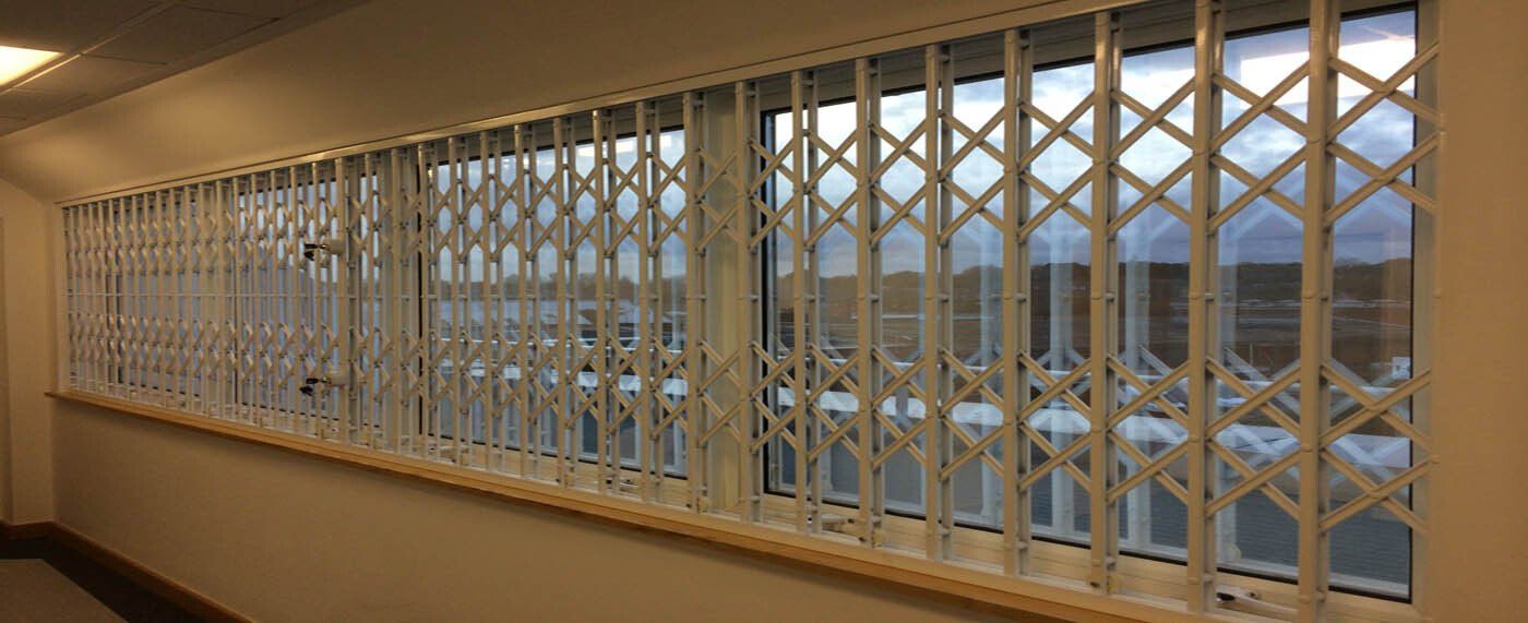 A long hallway with a row of windows and a metal gate.