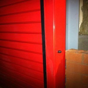 A close up of a red door with a black trim.