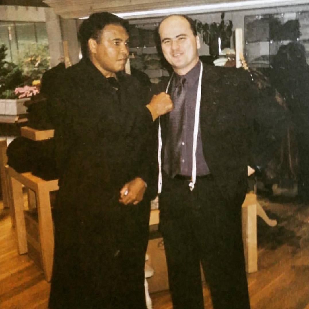 Muhammad Ali stands with Michael Duru in clothing store.