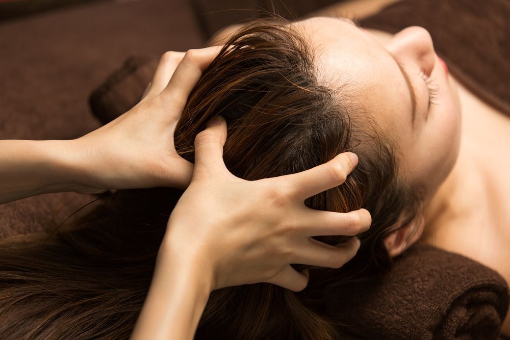 A woman is getting a head massage at a spa.