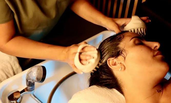 A woman is getting her hair washed in a sink.