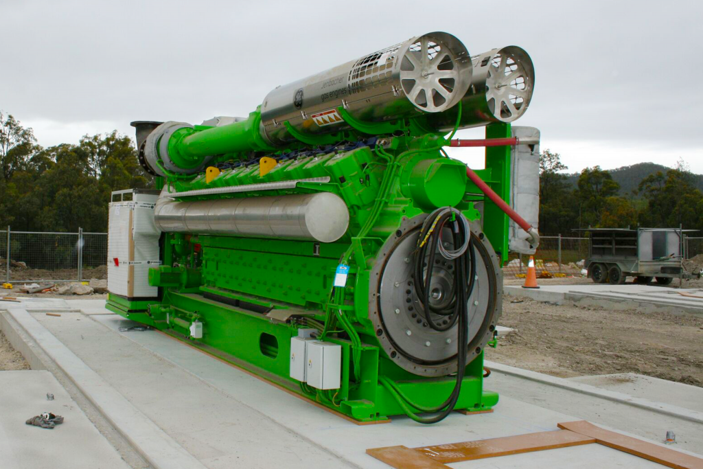 A large green engine is sitting on top of a concrete platform.