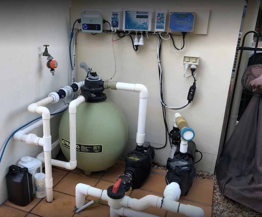 A swimming pool pump is sitting next to a sand filter.