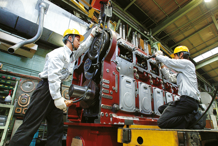 Two men are working on a large machine in a factory.