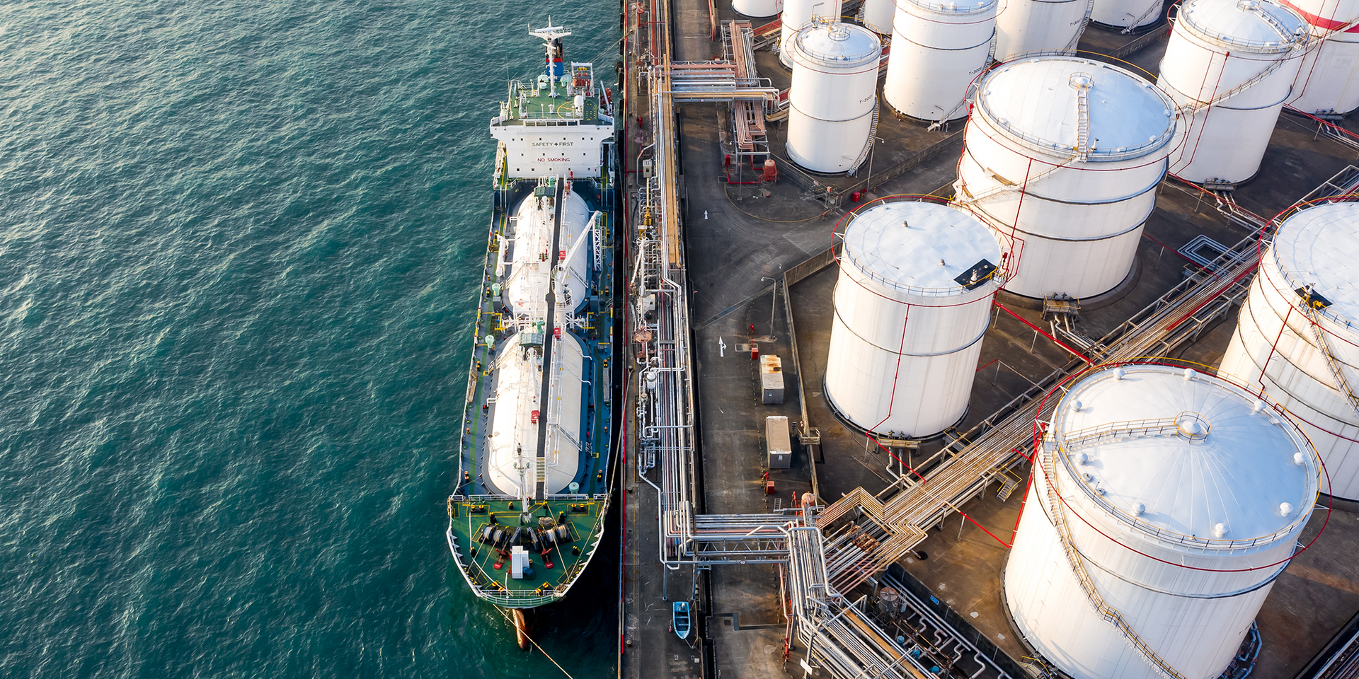 An aerial view of a oil refinery with a large ship docked next to it.