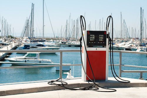 A gas pump in a marina with boats in the background