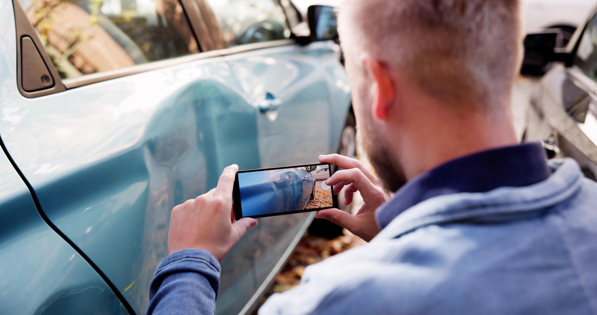 Man photographing vehicle damage to preserve evidence after a car accident Man photographing vehicle damage to preserve evidence after a car accident
