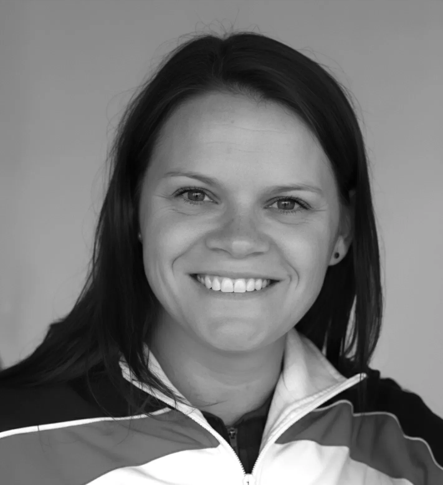 Smiling woman with dark hair wearing a jacket, looking at the camera.