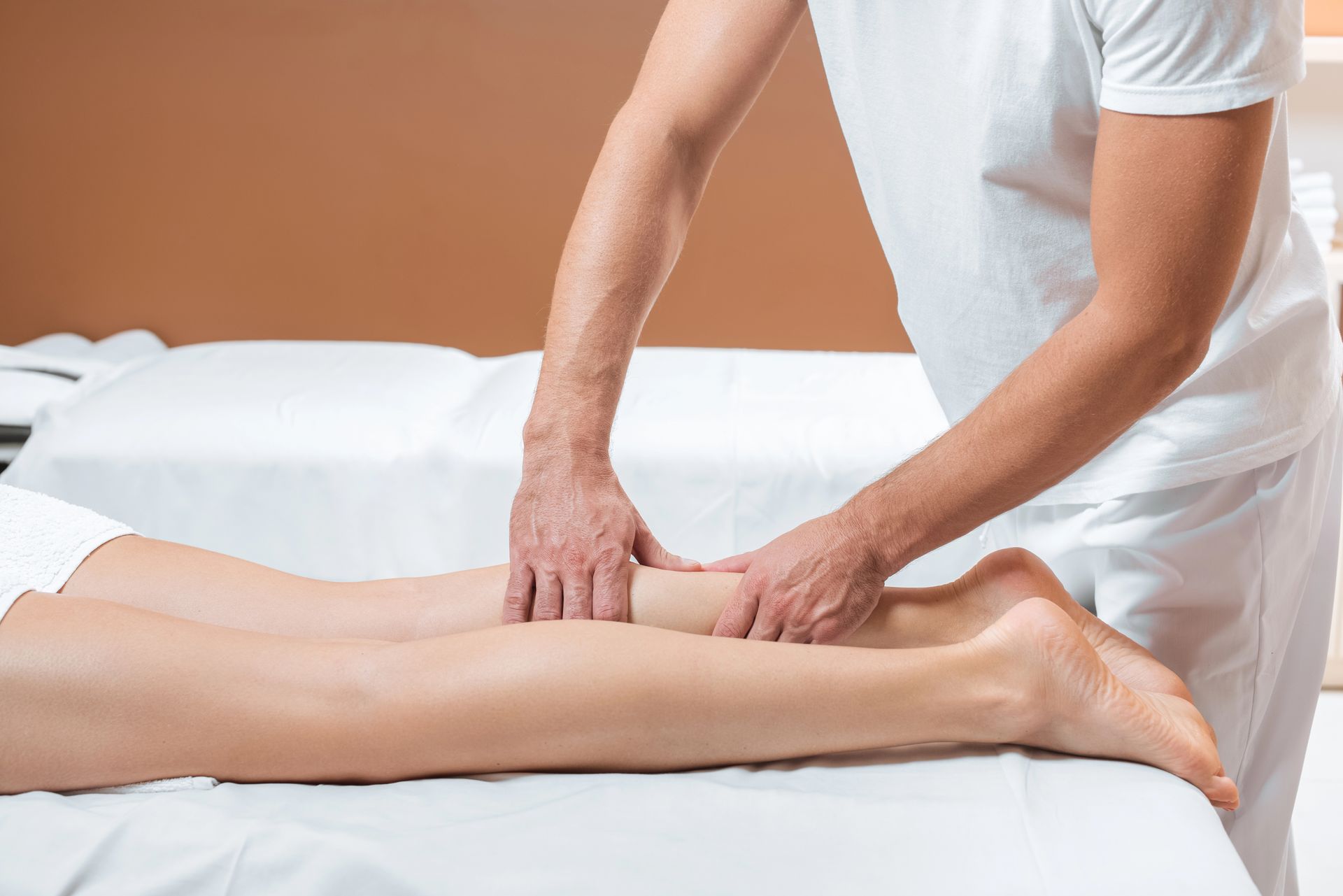 Persona che esegue un massaggio alle gambe in una spa. Le mani sono sul muscolo del polpaccio.