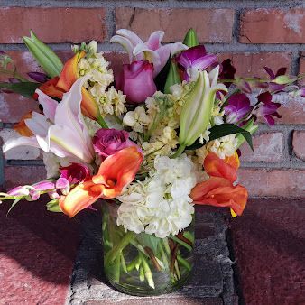 A vase filled with flowers is sitting on a brick wall.