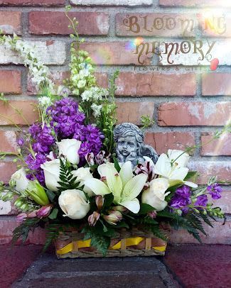 A basket filled with purple and white flowers and a picture of an angel.