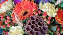 A close up of a bouquet of flowers with a lotus pod in the middle.