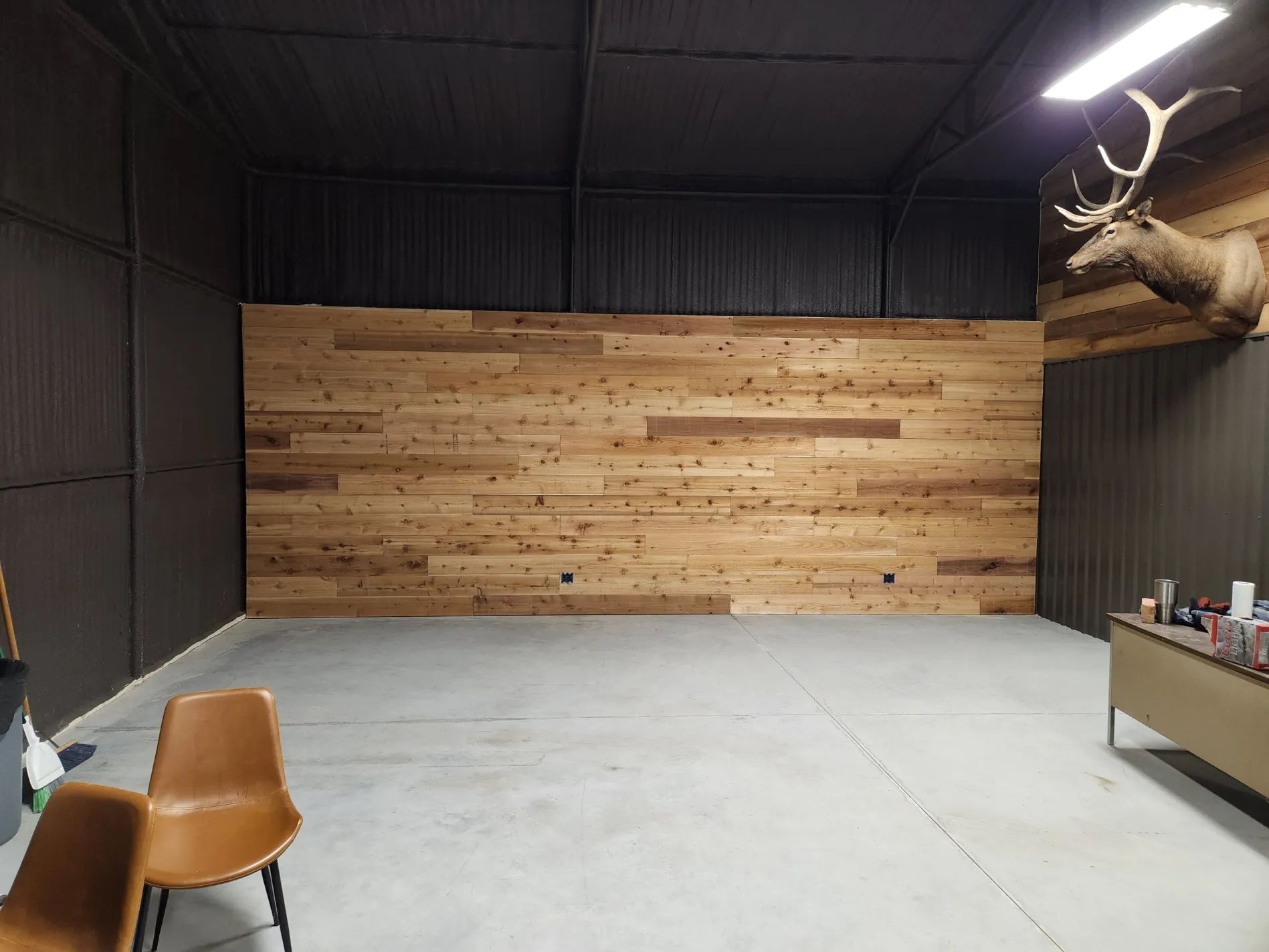 Interior of a workshop with a wooden accent wall, concrete floor, and mounted elk head.