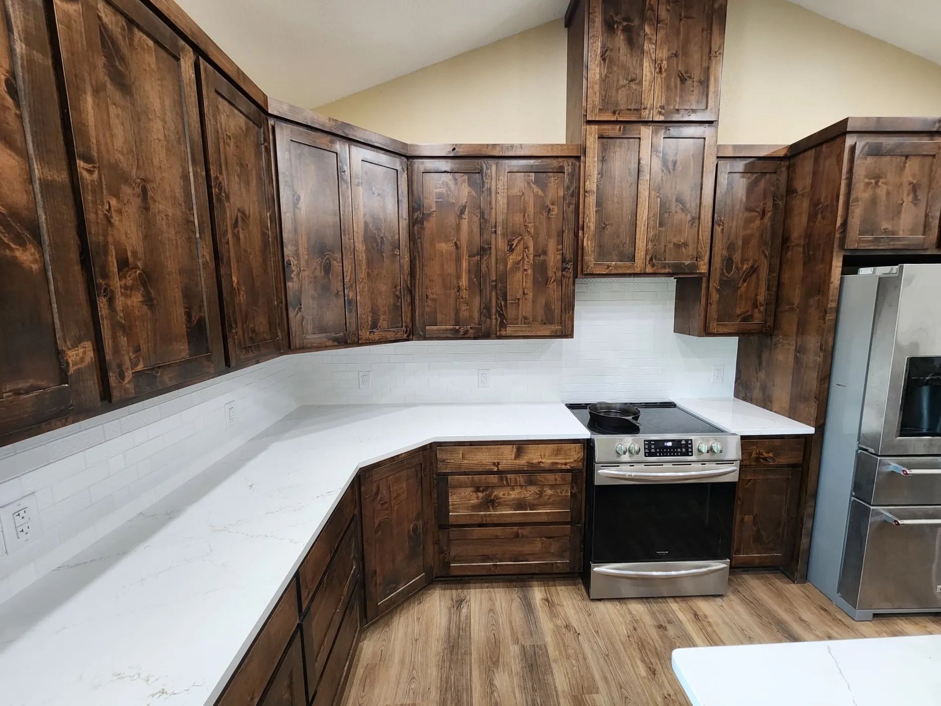 Kitchen with dark wood cabinets, white countertops, and stainless steel appliances.