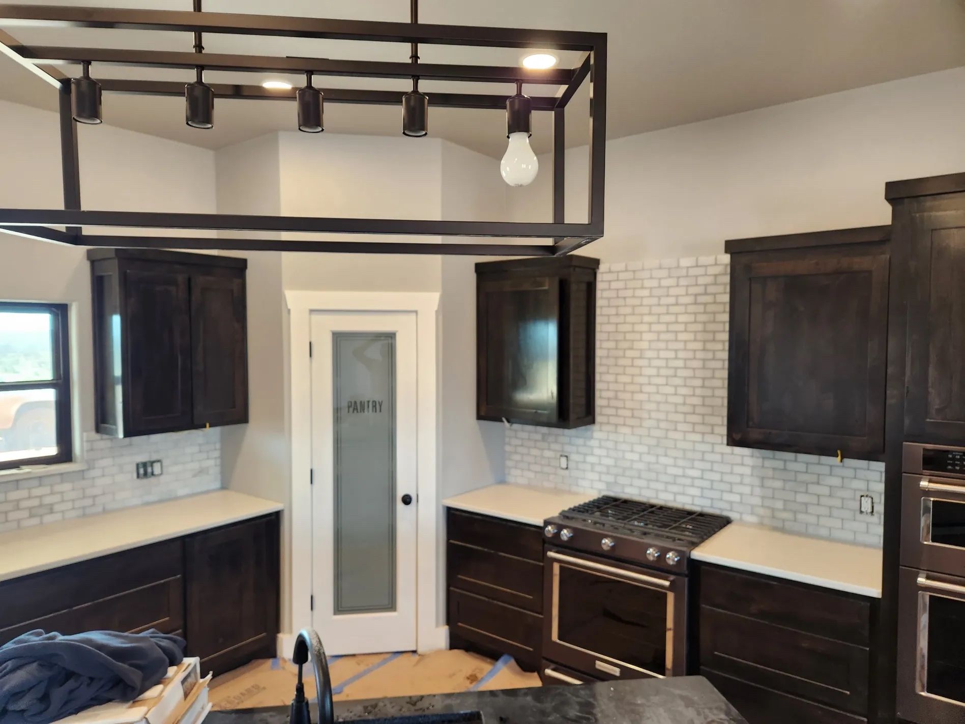 Kitchen with dark brown cabinets, white countertops, and a subway tile backsplash.