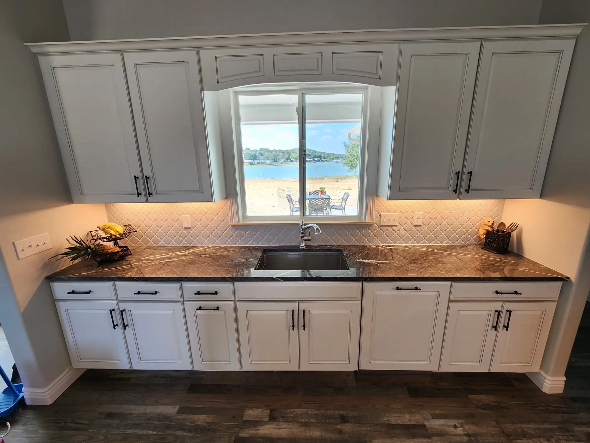White kitchen cabinets with a window overlooking water.