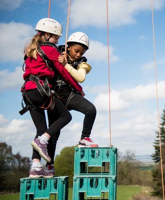Two young girls are standing on top of a stack of crates.