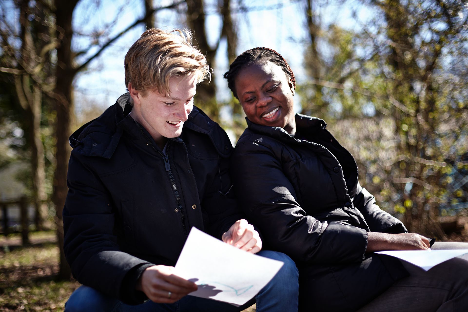 A man and a woman are sitting on the ground looking at papers.