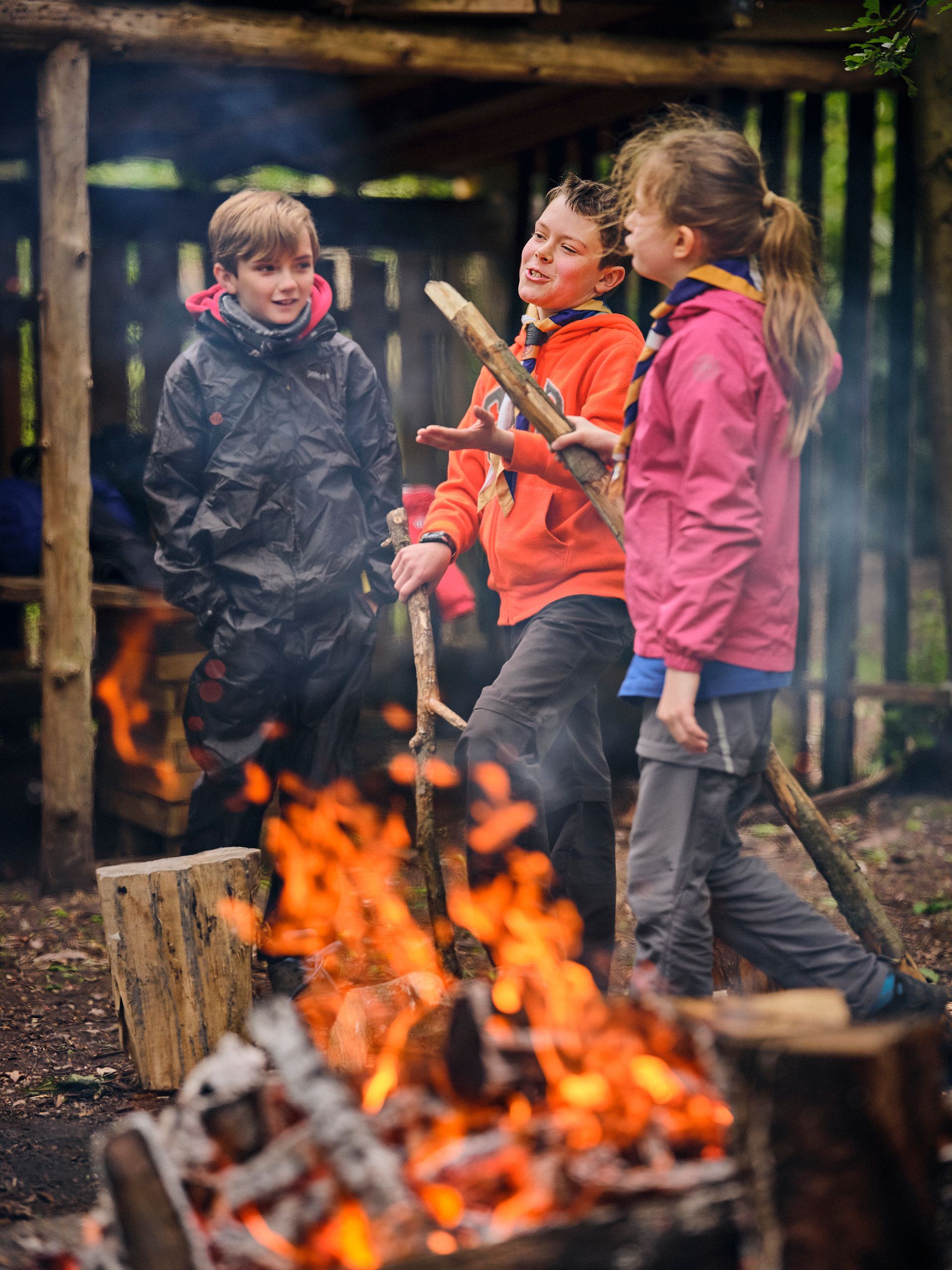 A group of children are standing around a campfire.