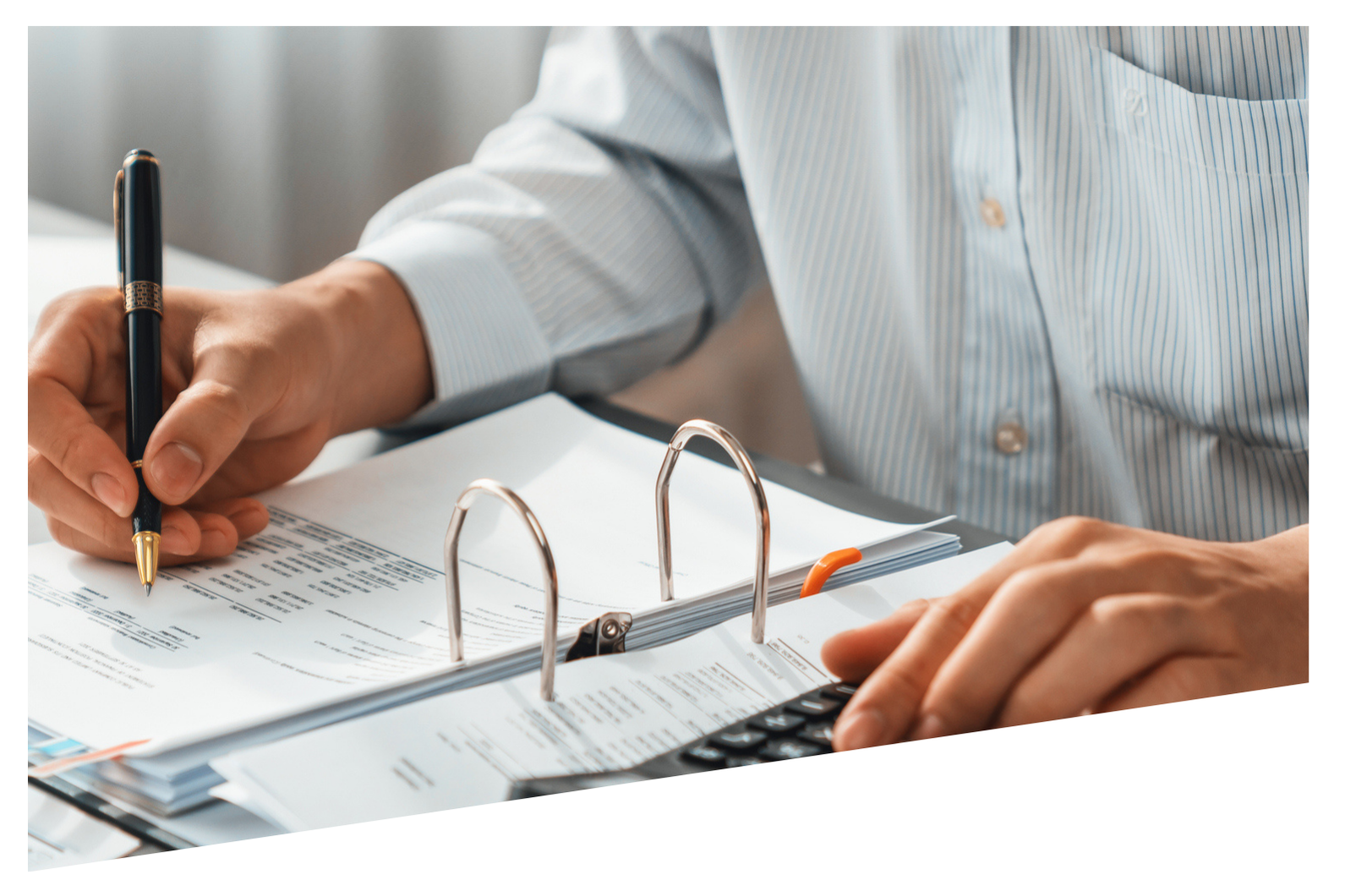 A man is writing on a piece of paper while using a calculator.