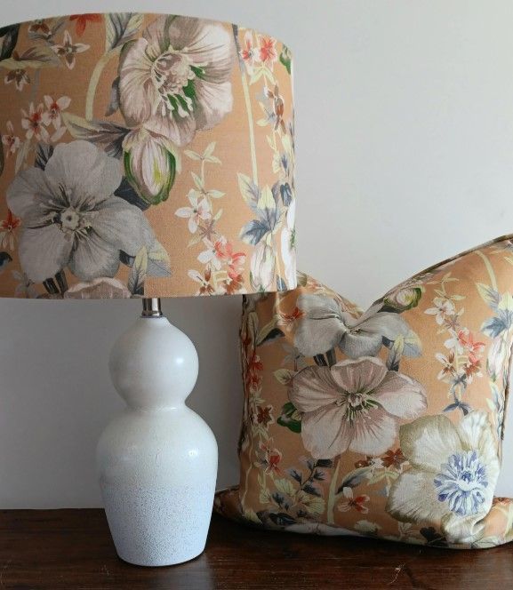 A lamp with a floral shade sits next to a pillow