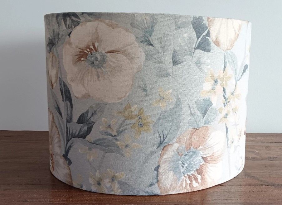 A lamp with a plaid shade sits next to a floral pillow