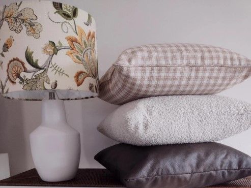 A stack of pillows next to a lamp with a floral shade