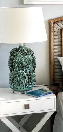 A lamp is sitting on a white nightstand next to a bed.