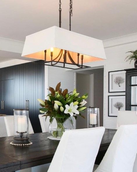 A dining room table with a vase of flowers and candles on it