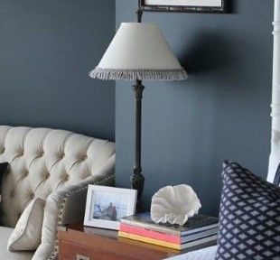 A lamp is sitting on a nightstand in a living room next to a couch.