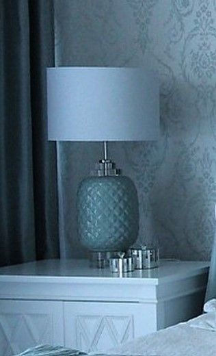A lamp is sitting on a nightstand next to a bed.