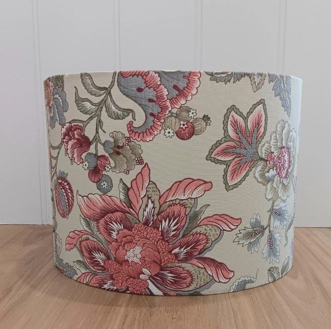 A lampshade with a floral pattern is sitting on a wooden table.