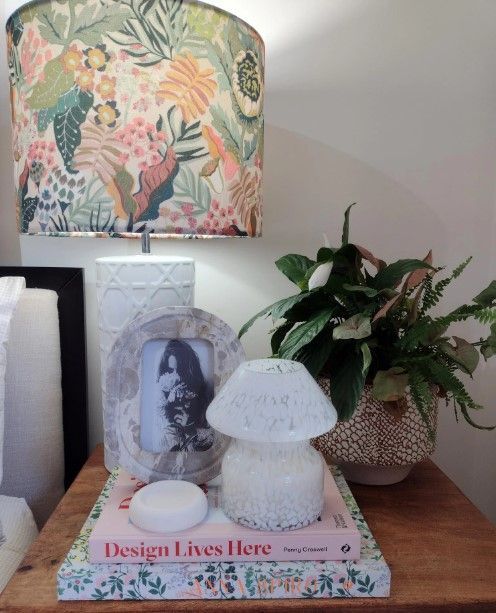 A book titled design lives here sits on a table next to a lamp