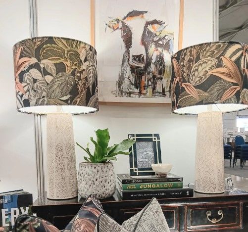 A table with two lamps and a picture of a cow on the wall