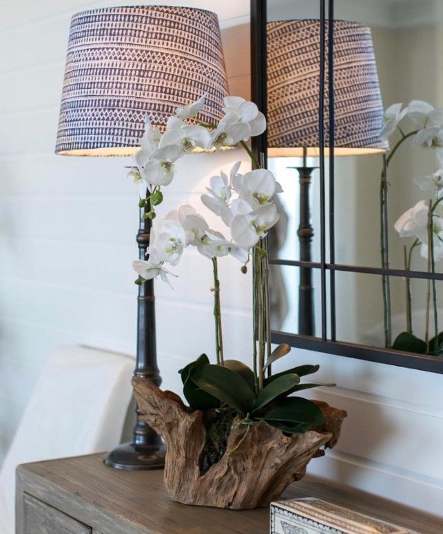 A vase of flowers sits on a table next to a lamp