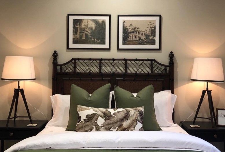 A bedroom with a bed and two lamps and two pictures on the wall above the bed