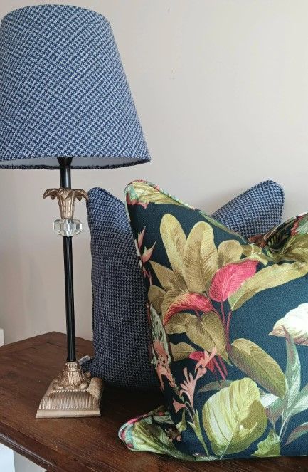 A lamp and two pillows are on a wooden table.