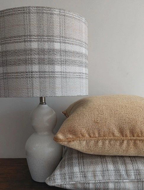 A lamp is sitting on a table next to a stack of pillows.