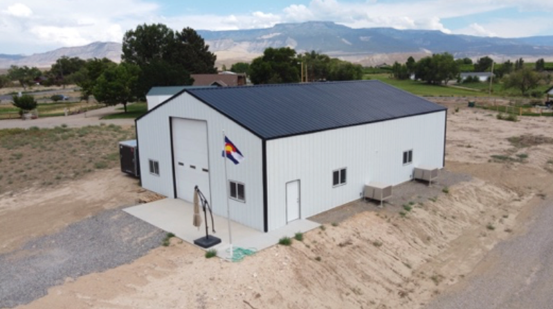 An aerial view of a large white building with a black roof.