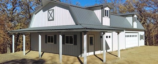 A large white house with a gray roof and a porch.