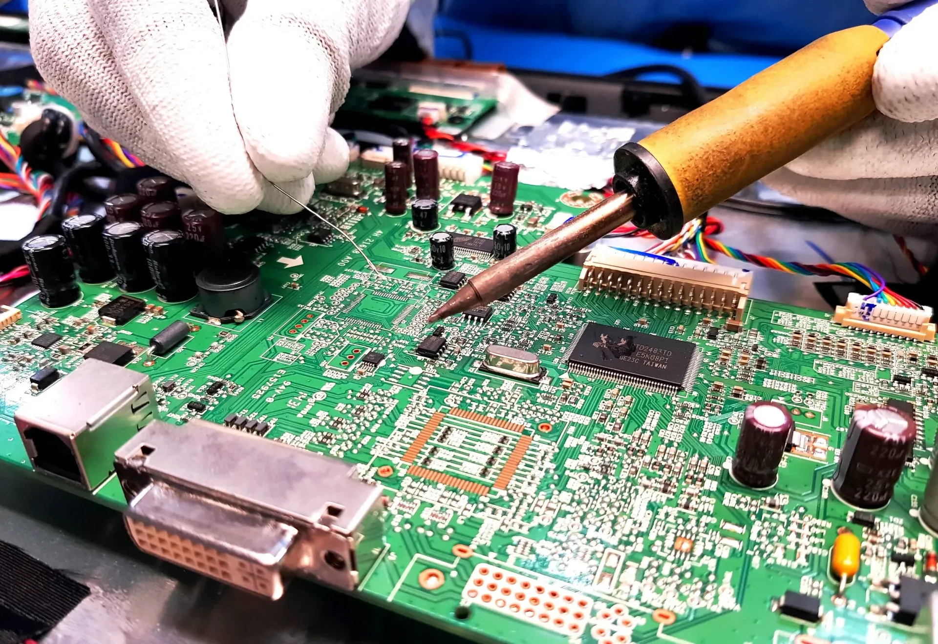 Mechanic fixing exercise equipment, wearing gloves, surrounded by tools, gym setting.