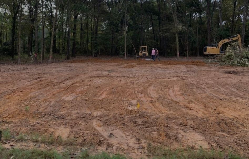 A large dirt field with a bulldozer in the background.